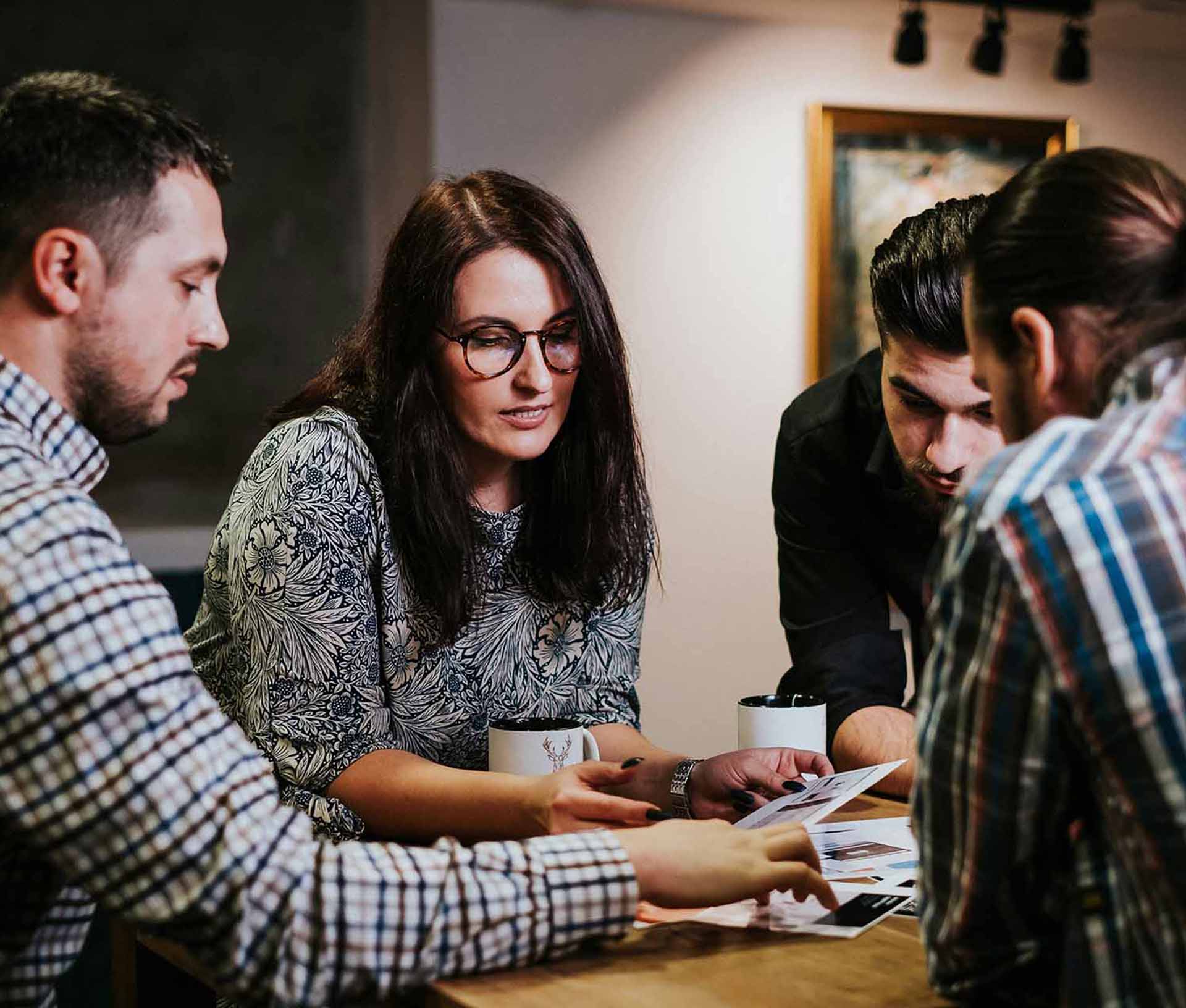 Une équipe de professionnels réunie autour d'une table, examinant des photographies et des documents imprimés. Cette scène illustre la collaboration, la planification et la prise de décision collective dans un contexte professionnel.