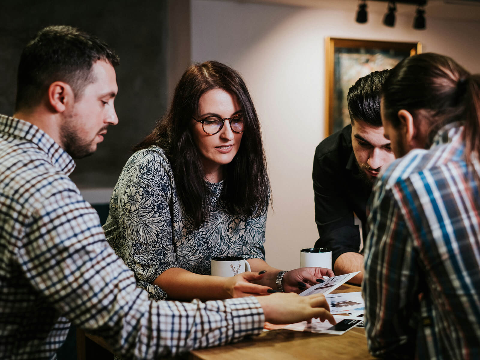 Team of researchers and designers collaborating around a table with historical documents, maps, and digital screens to develop the Plan-les-Ouates heritage app.